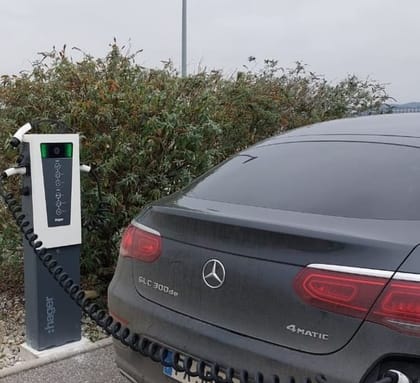 Voiture électrique en charge, câble spiralé branché sur une borne sur pied