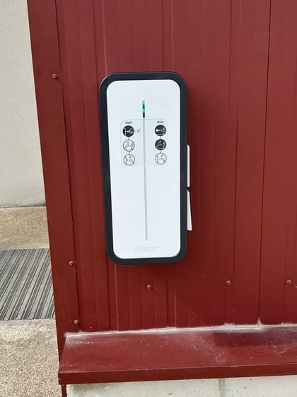 Borne de recharge murale fixée sur un bardage extérieur rouge
