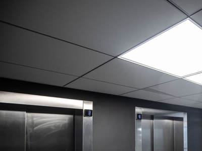 Dalle LED allumée au plafond du palier d'ascenseurs d'un immeuble