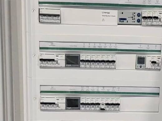 Tableau de répartition ouvert, disjoncteurs alignés sur leurs rails