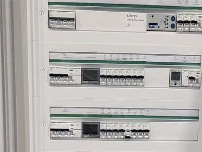 Tableau de répartition ouvert, disjoncteurs alignés sur leurs rails
